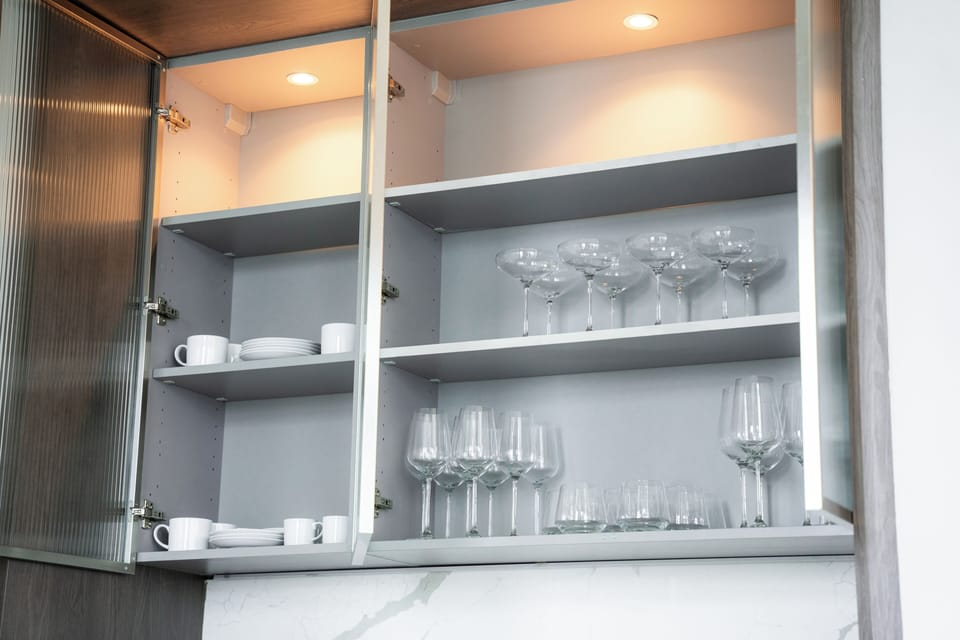 Bar stocked with white, red, hip glasses, a cocktail set, and an espresso machine with latte and espresso cups