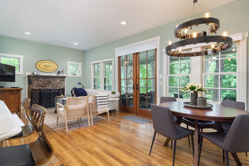 Through those French doors lies a living and dining space, anchored by a stone fireplace.