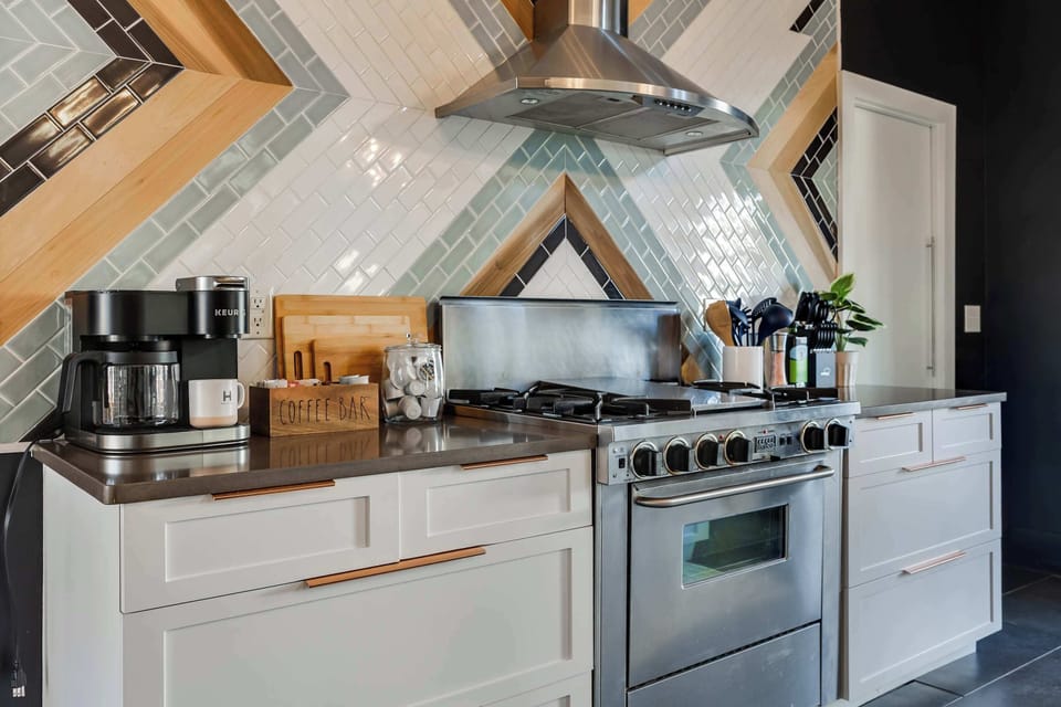 This beautifully designed kitchen features a professional-grade gas range, stainless steel hood, and a bold geometric backsplash that brings personality and style to the heart of the home.