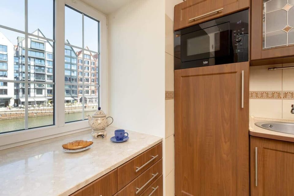 A wooden kitchen with a window ledge used as additional shelf space. The cabinetry and finishes give the space a classic, rustic touch.