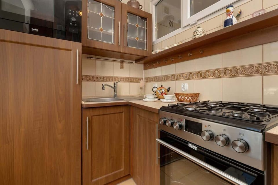 A close-up of the kitchen’s built-in microwave, wooden cabinetry, and tile backsplash. The countertop provides ample workspace for cooking.