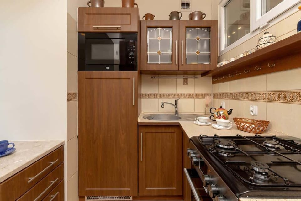 A close-up of the kitchen’s built-in microwave, wooden cabinetry, and tile backsplash. The countertop provides ample workspace for cooking.