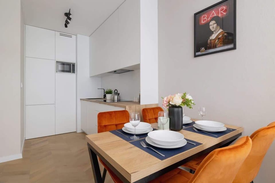 A view of the dining table set for a meal, with vibrant chairs and wall art in the background.