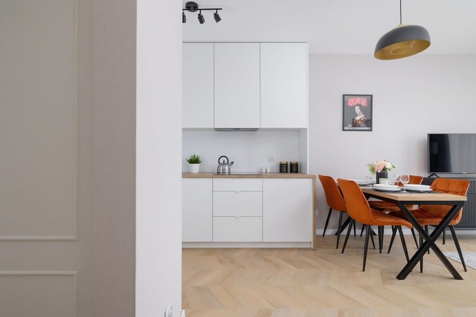 A minimalist kitchenette featuring a kettle, open cabinetry, and integrated appliances.