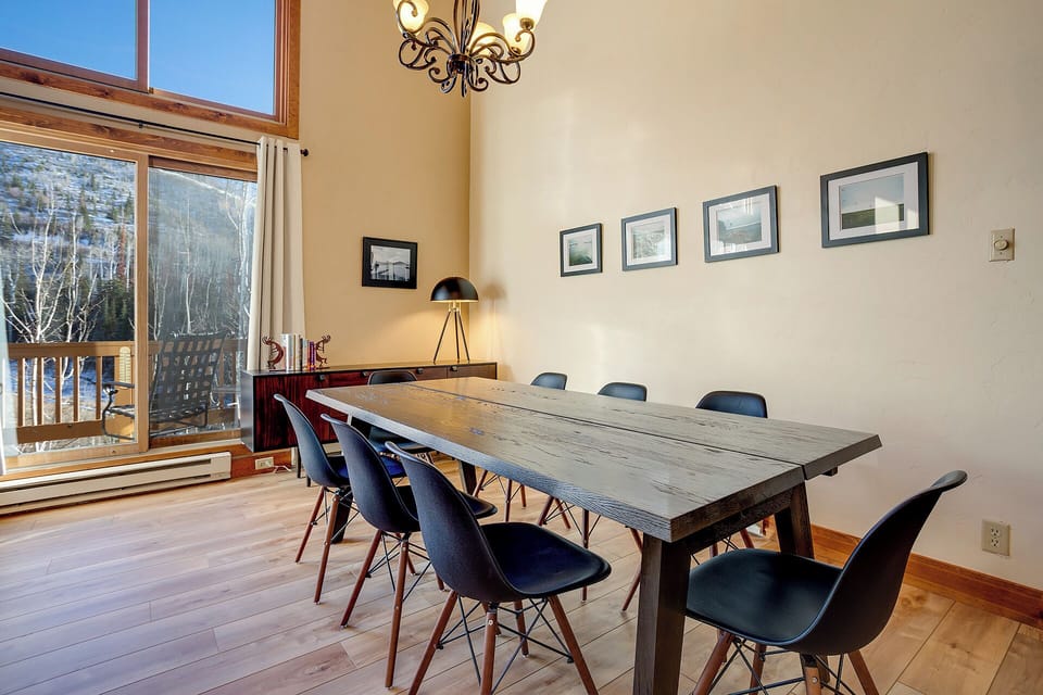Gather around your spacious dining table where rustic meets modern style, perfect for memorable meals with mountain views streaming through tall windows.