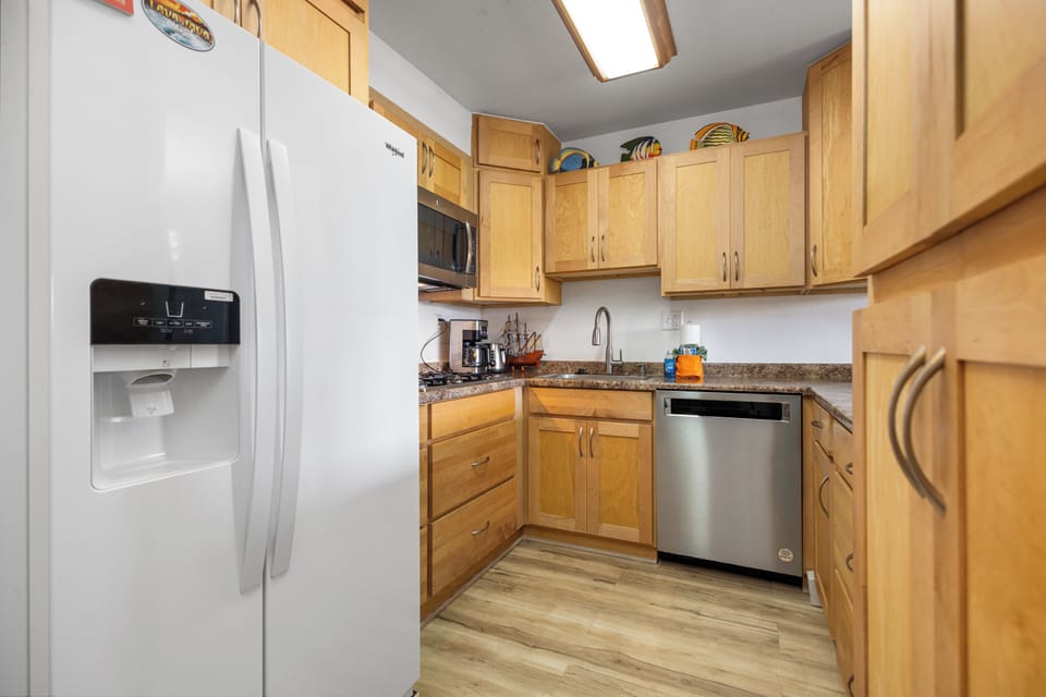 Your fully-equipped kitchen awaits with modern appliances, warm wood cabinetry, and granite countertops—perfect for whipping up meals or morning coffee at your leisure.