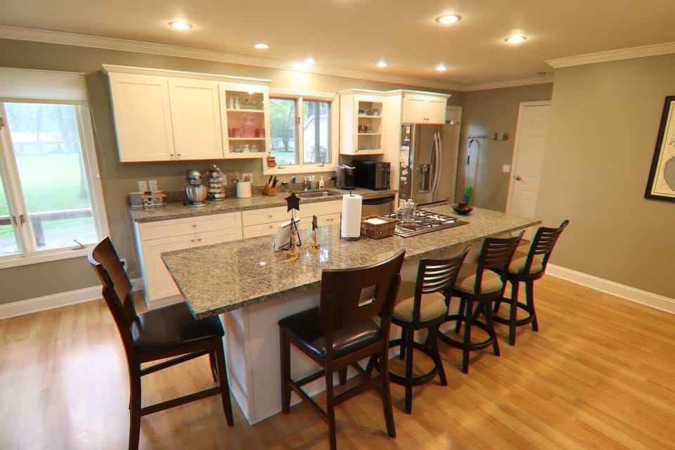 This modern kitchen provides an island used for both a breakfast nook and space for cooking. Enjoy stainless steel appliances, a gas stove, and views overlooking the backyard. 
