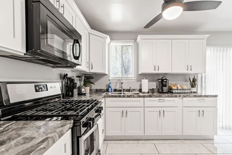 Modern kitchen featuring a ceiling fan, gas stove, oven, fridge, freezer, microwave, Keurig coffee station, and more.