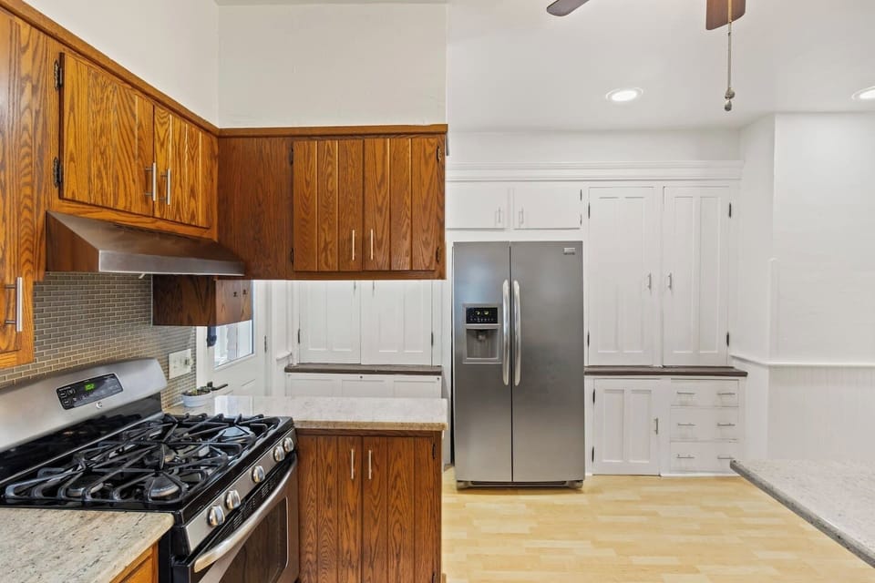 Kitchen -Spacious kitchen with a stainless steel gas stove, ample wooden cabinetry, and a large refrigerator. Ideal for cooking and entertaining.