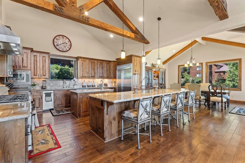 This kitchen has a large island for prep and entertaining, rustic beams, and modern finishes.
