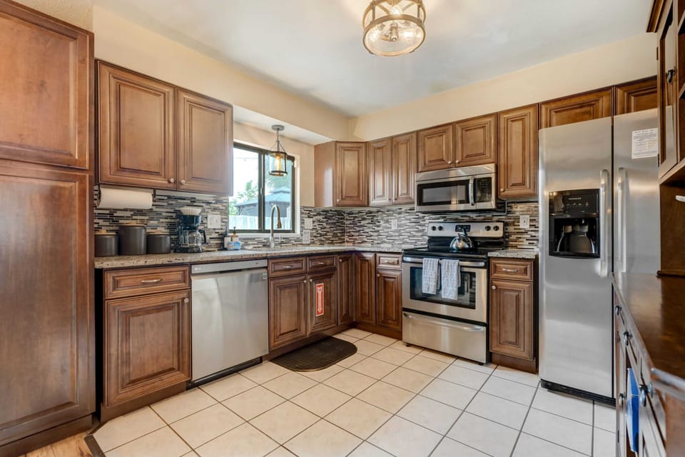 Wood cabinets and a full set of appliances line this kitchen, giving you plenty of room to prep and cook. Natural light from the window brightens the tile floors and counters while meals come together.