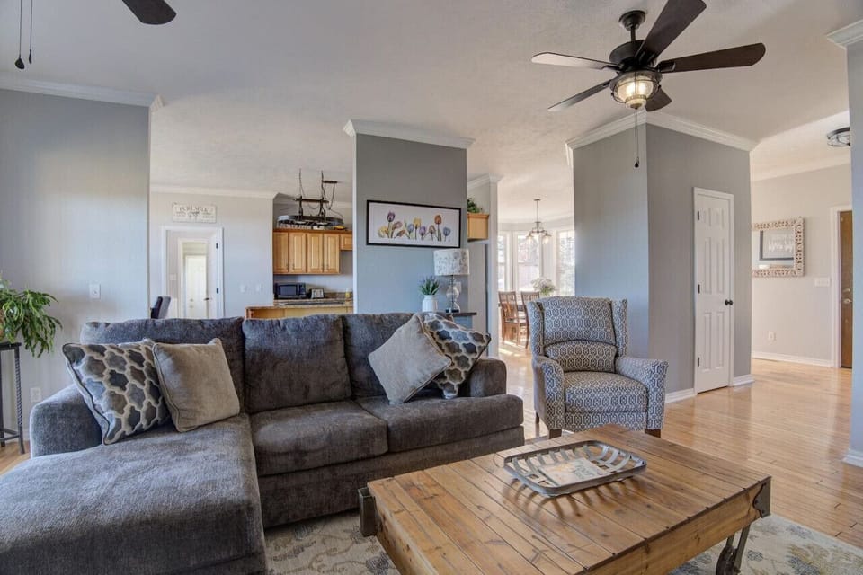 Elegant living room scene with comfortable gray couches, throw pillows, a wooden center table, and tasteful wall art on a wooden floor.