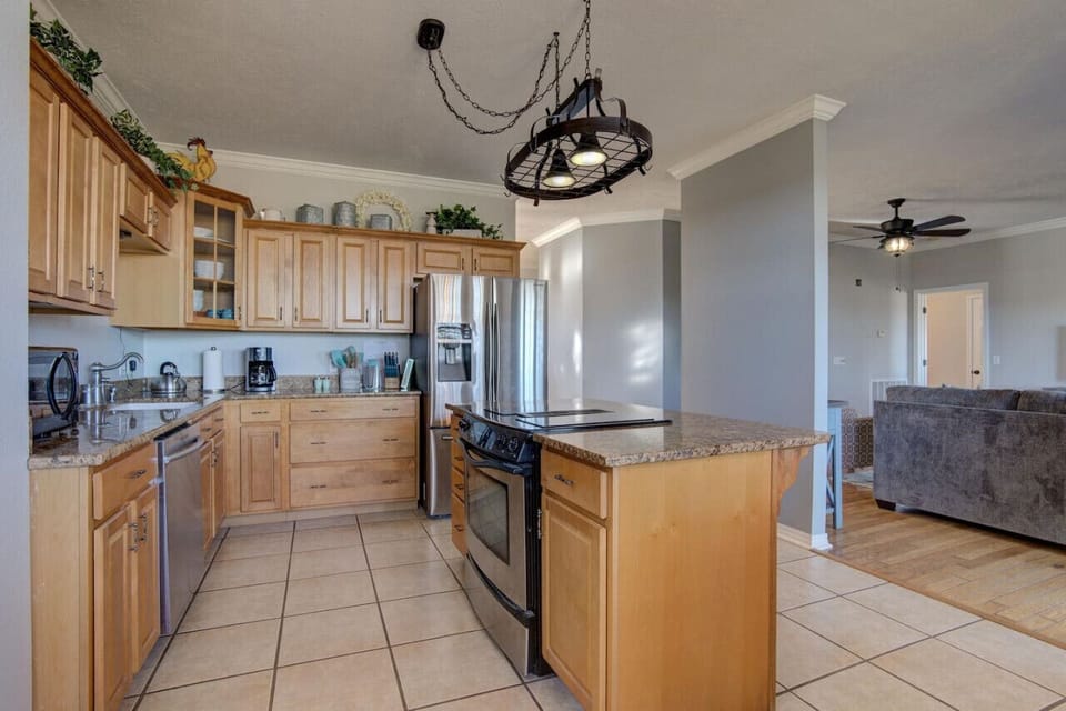 Functional kitchen layout: island counter with built-in wooden cabinets and stove, a fridge, extra cabinets, and everything you need for cooking.