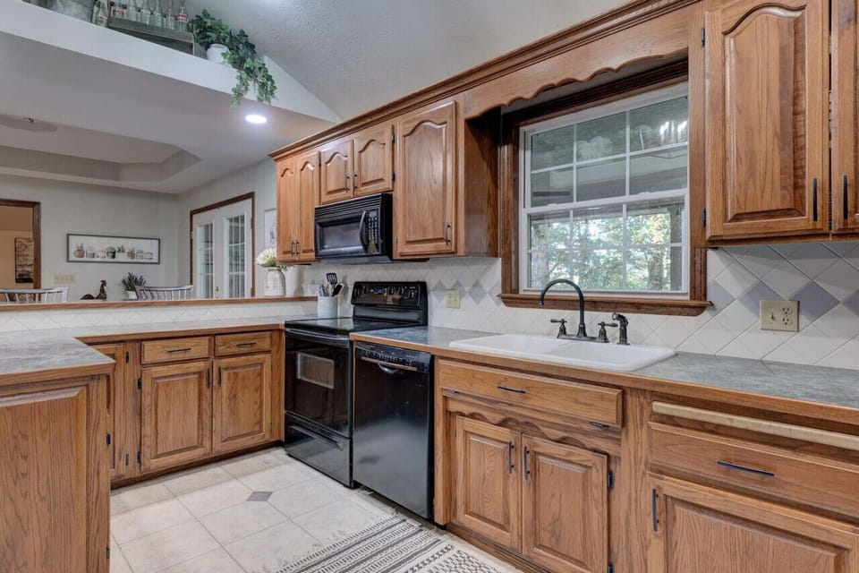 Stylish kitchen space with well-crafted wooden cabinets, a microwave, oven, stove, and a bright glass window to brighten your cooking experience.