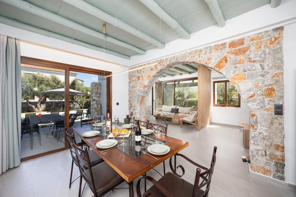 Open-plan living room with sofa, dining area, kitchen, indoor pool, ornamental fireplace, A/C, WiFi internet, and satellite TV