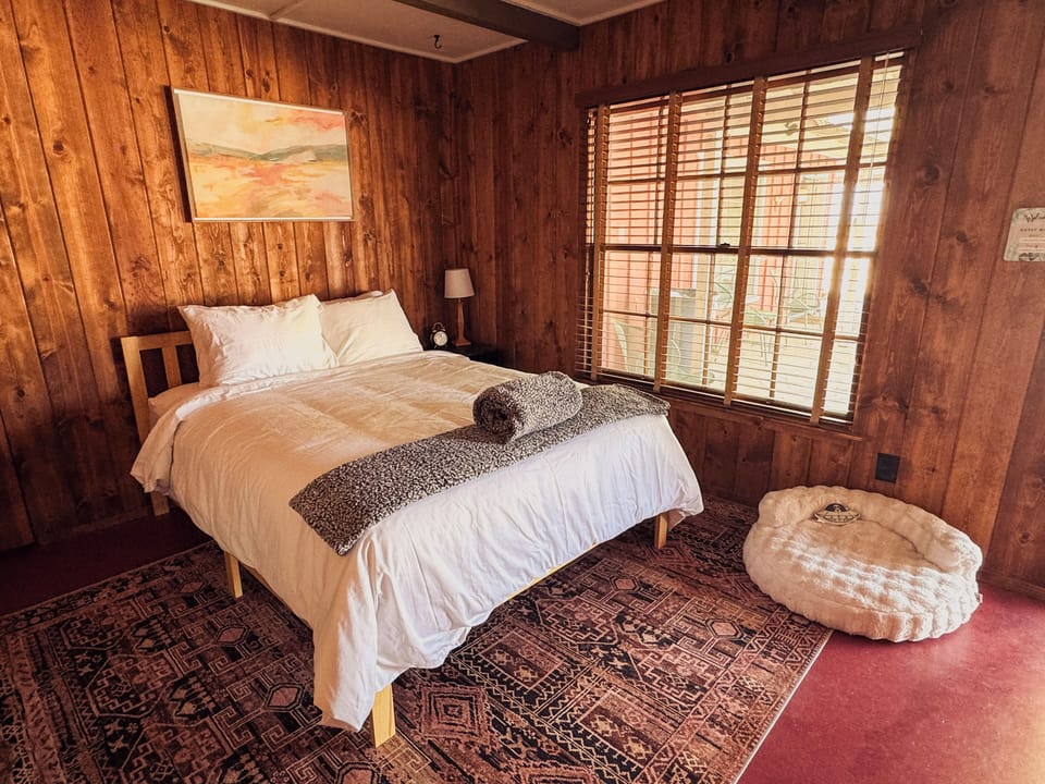 Cozy queen bed with window view, dog bed, and desert-inspired decor (2)