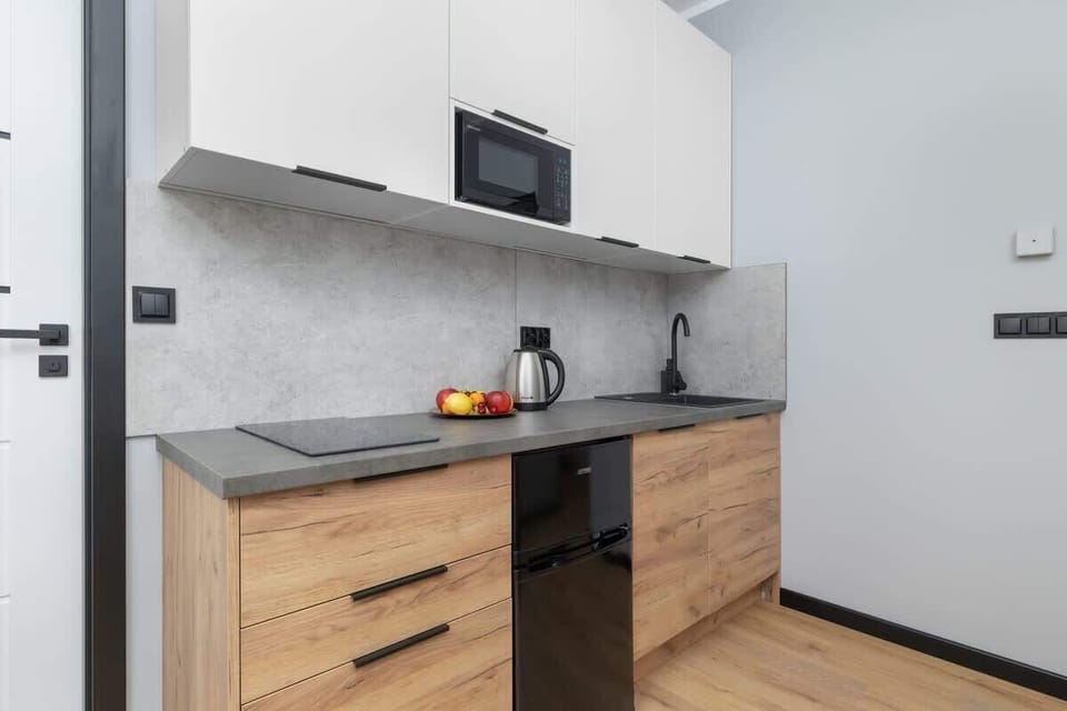 A wider view of the kitchen showing modern cabinetry and all essentials. A compact space for convenient cooking.