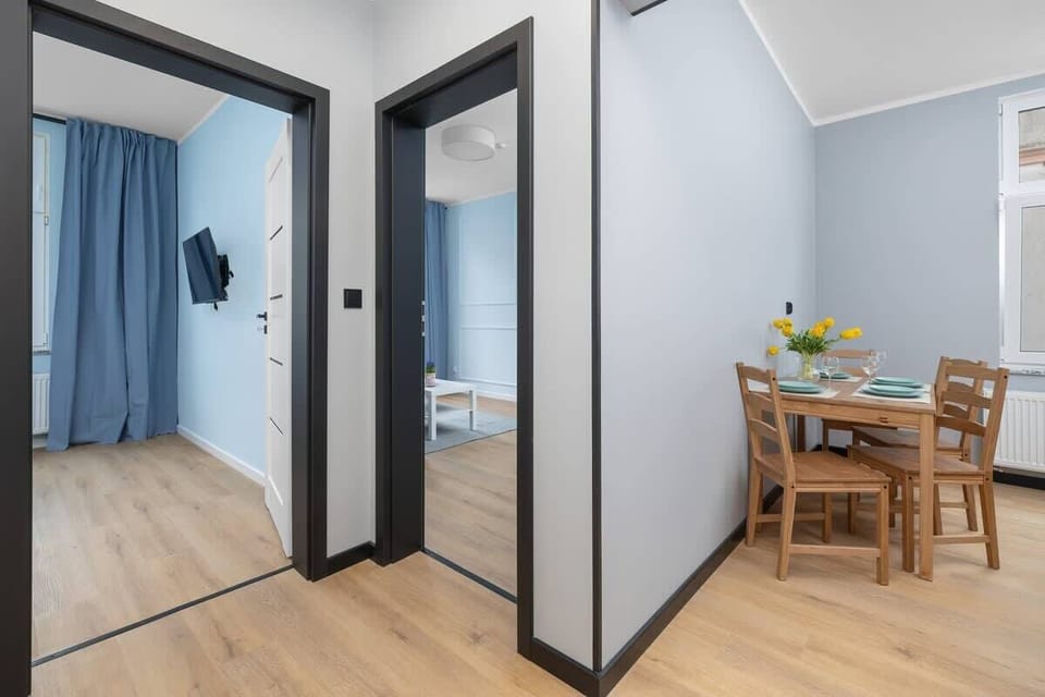 A hallway view with light wood flooring leading into the dining area. Open and functional layout.