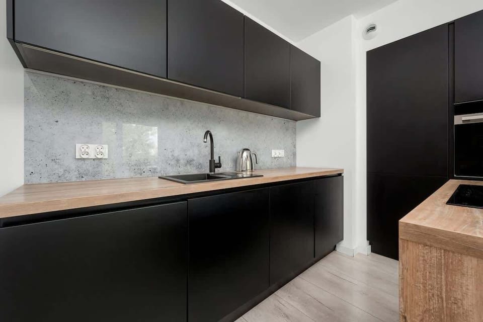 Sleek kitchen designed with matte black cabinets, wooden counters, and built-in appliances.