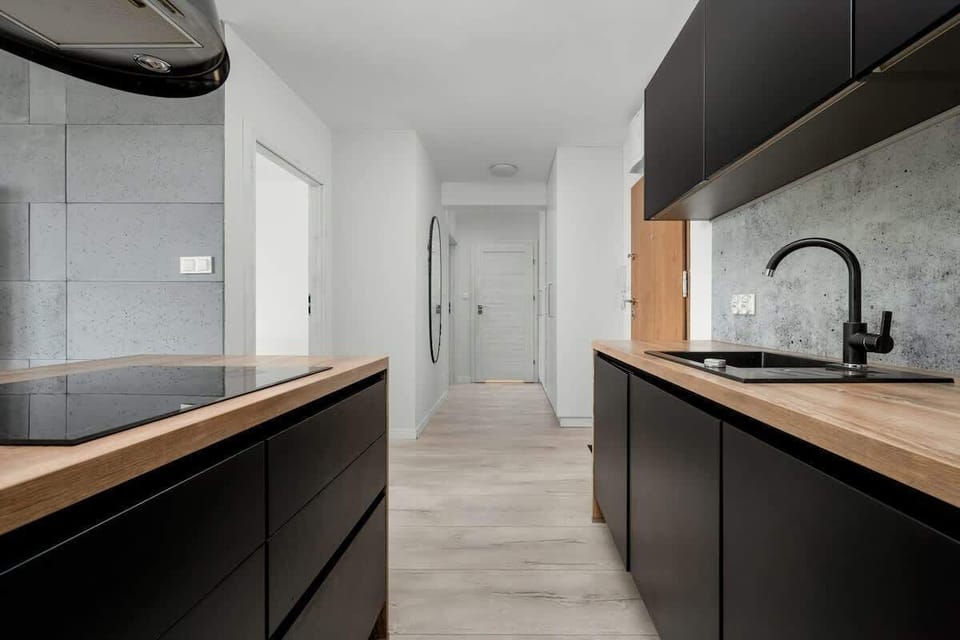 Sleek kitchen designed with matte black cabinets, wooden counters, and built-in appliances.