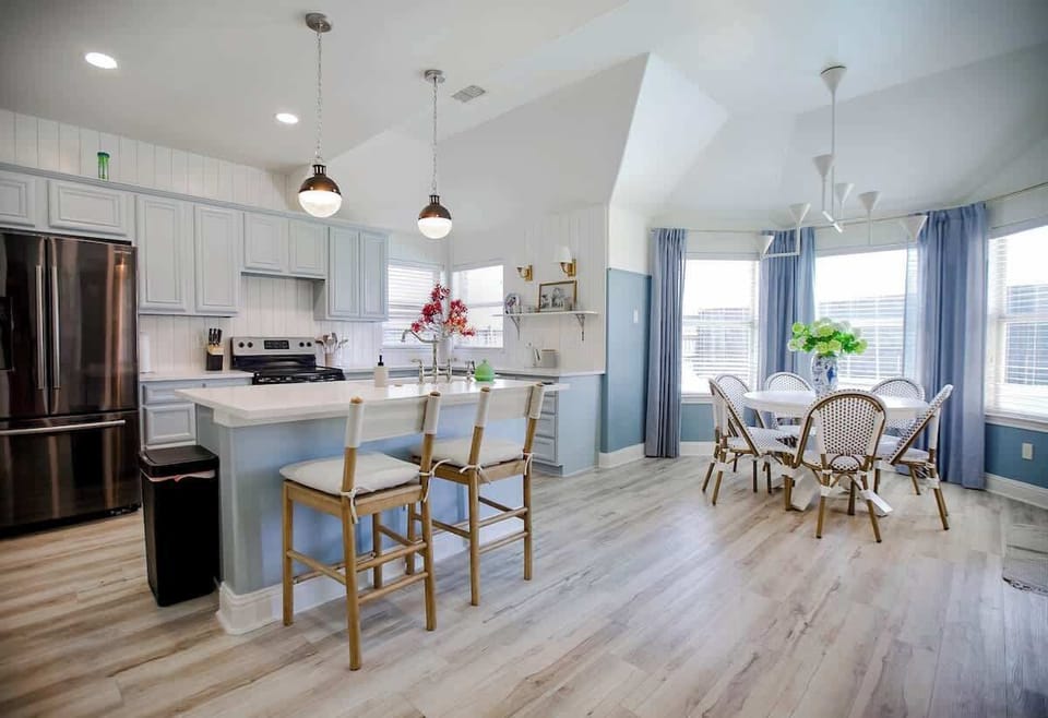 Unlock your inner chef in the stylish, fully equipped kitchen island with seating for three. Enjoy delightful meals with family and friends at the six-seat round dining table, overlooking the serene pool area.