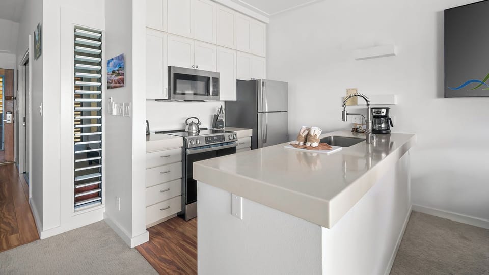 Step into your sleek, modern kitchen featuring stainless steel appliances, gleaming quartz countertops, and ample cabinet space for preparing delicious meals during your stay.