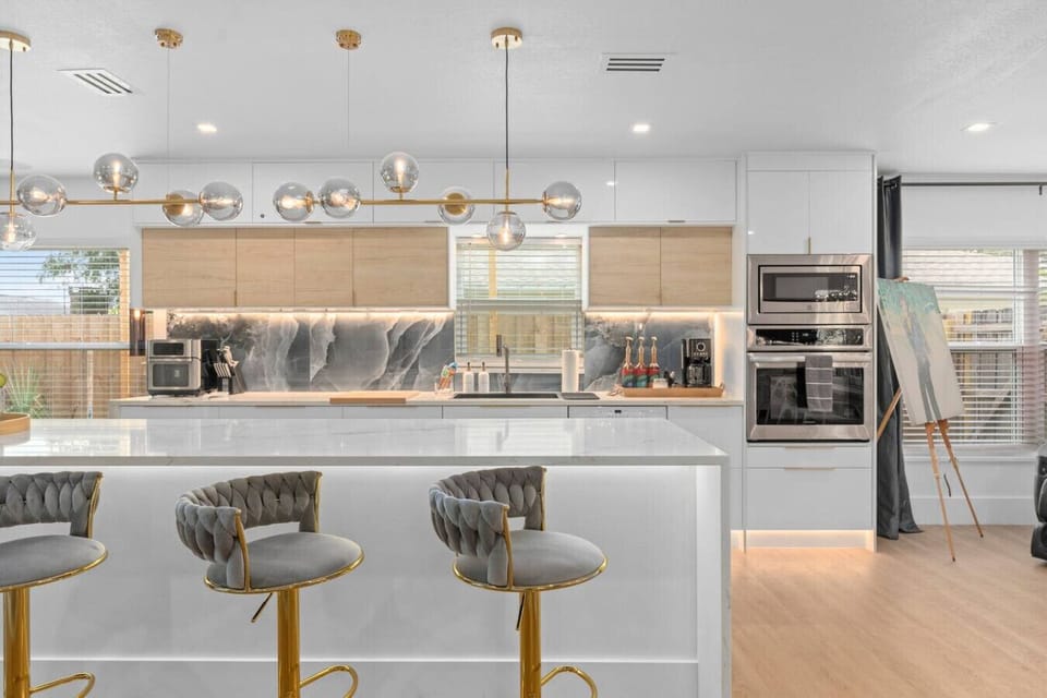 Modern kitchen with marble waterfall island, gold globe pendant lights, velvet bar stools and stainless appliances, Bird House Spa Winter Park