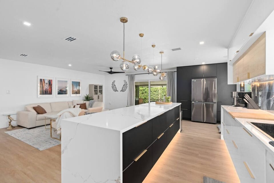 Modern gourmet kitchen with marble island, globe chandelier and dark cabinetry, Winter Park vacation home