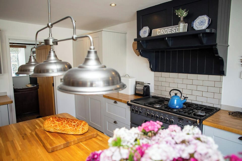 Kitchen with cooker and cooker hood, island unit with bread and flowers