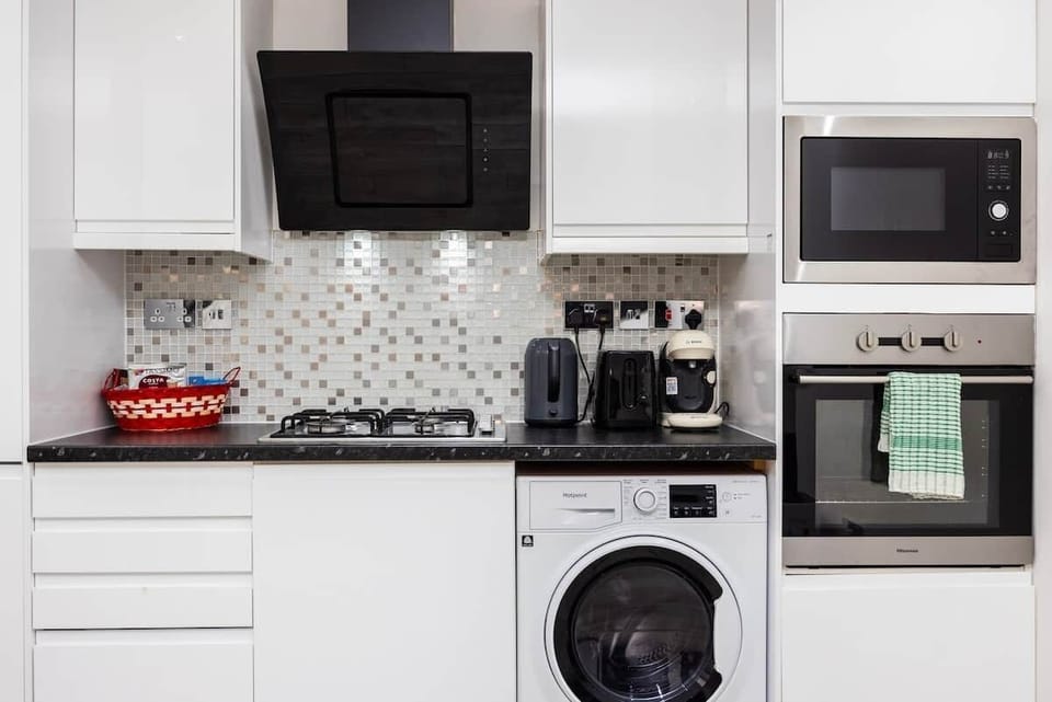 Whip up family meals in this sleek, modern kitchen featuring a gas stovetop and a high-end built-in oven. It is fully equipped with a microwave and toaster to cover all your cooking needs.