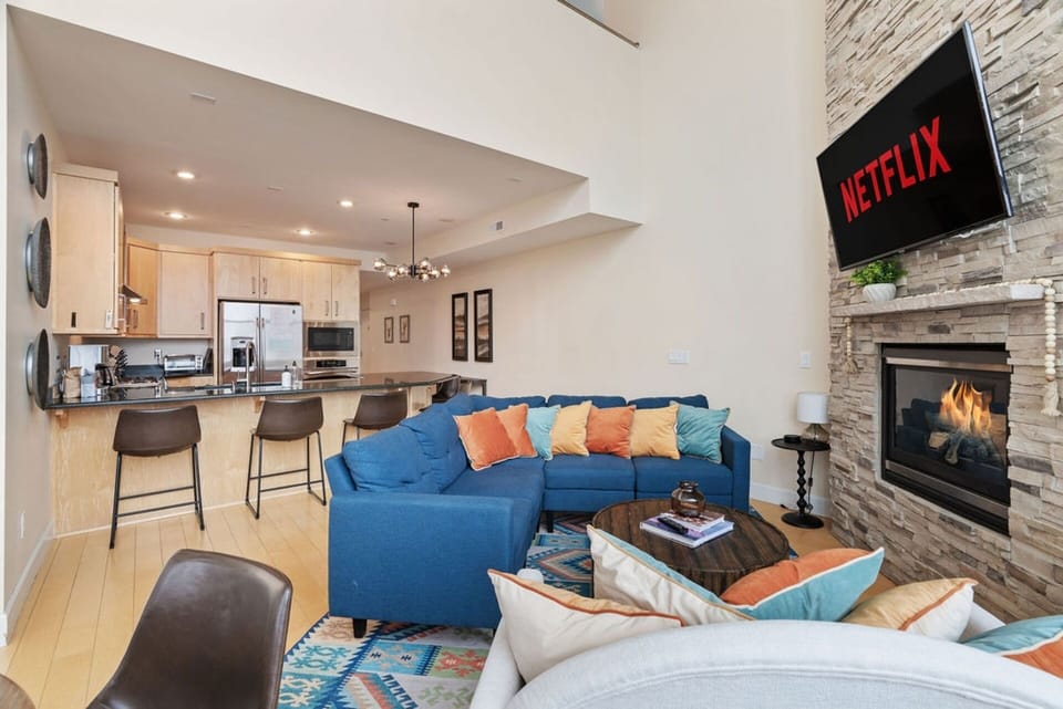 Cozy up by the fireplace in this bright living room! Enjoy remote-controlled blinds and floor-to-ceiling windows letting in lots of sunshine! | The Juniper, Brian Head, Utah | Voyax Luxury Vacation Rentals
