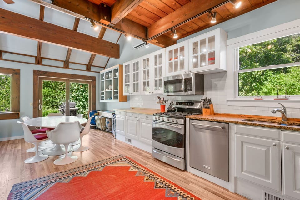 The stainless steel appliances and stark white cabinetry of the kitchen lend themselves to the progression toward the modern dining table with seating for six