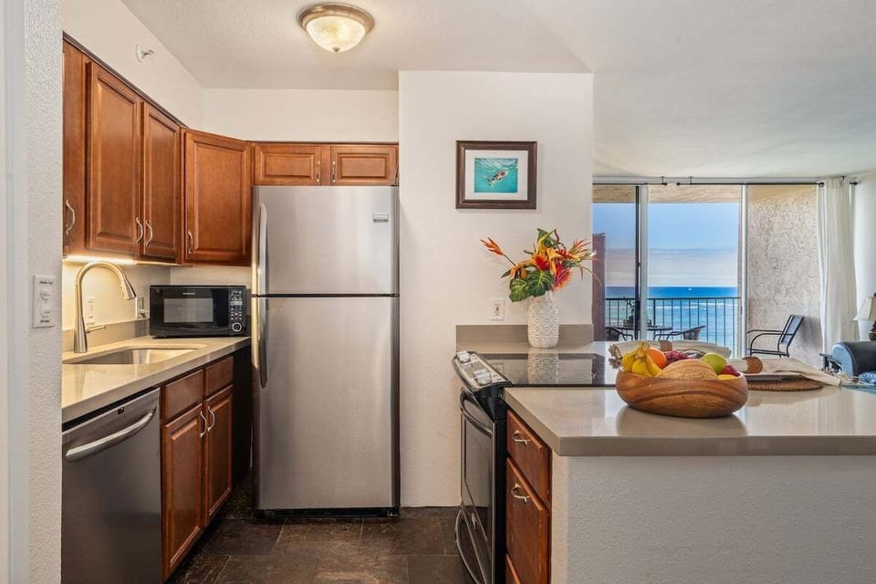 Cook in a kitchen framed by wood and steel, fruit and flowers adding a fresh touch.