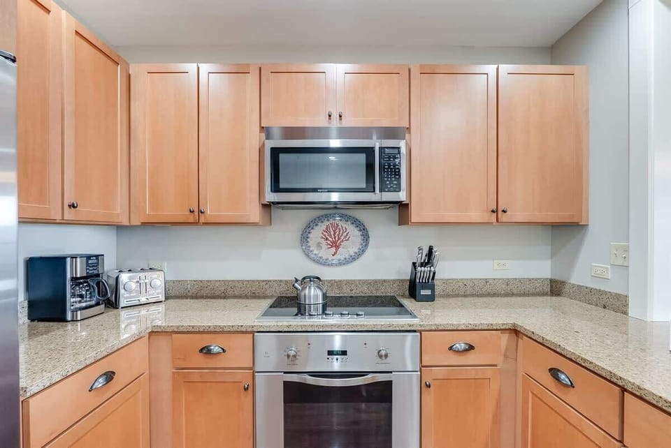 - Warm wood cabinetry offers plenty of storage, paired with sleek granite countertops - Stainless appliances, including a built in oven and microwave, make cooking a breeze - Charming coral plate and coffee station complete the setup