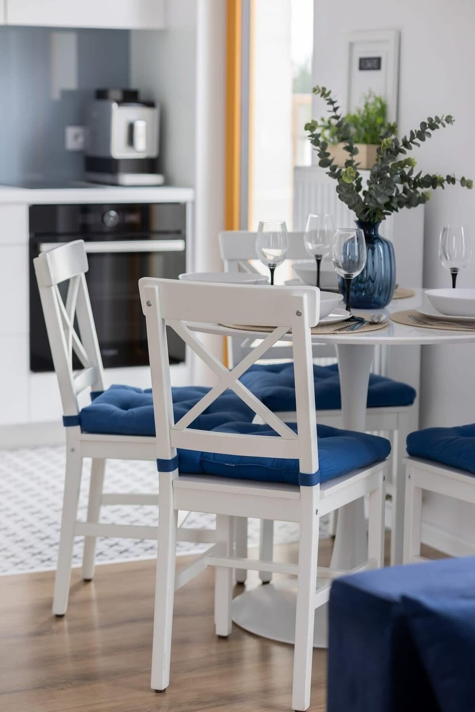 A dining area with white chairs and navy accents creates an elegant, coastal atmosphere.

