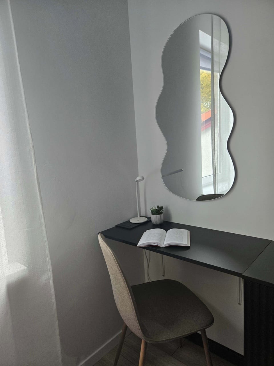 Comfortable desk with chair and decorative mirror on the wall.