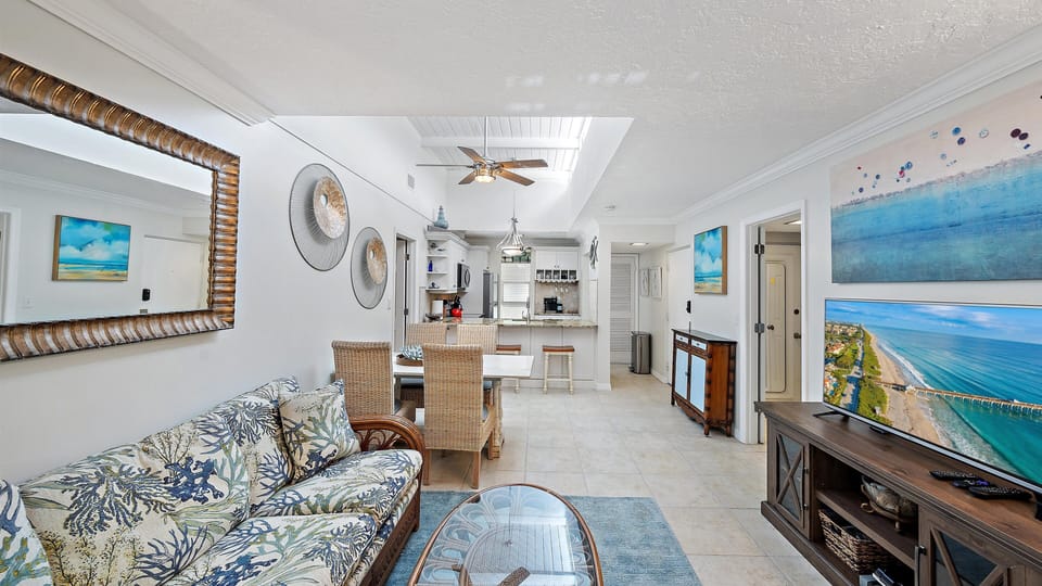 This expansive view showcases the bright, open-concept design that connects the living area, fully-equipped kitchen, and dining space, perfect for gathering during your Longboat Key getaway.