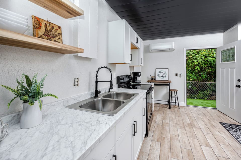 Bright kitchen with marble counters, open shelves, and modern appliances.