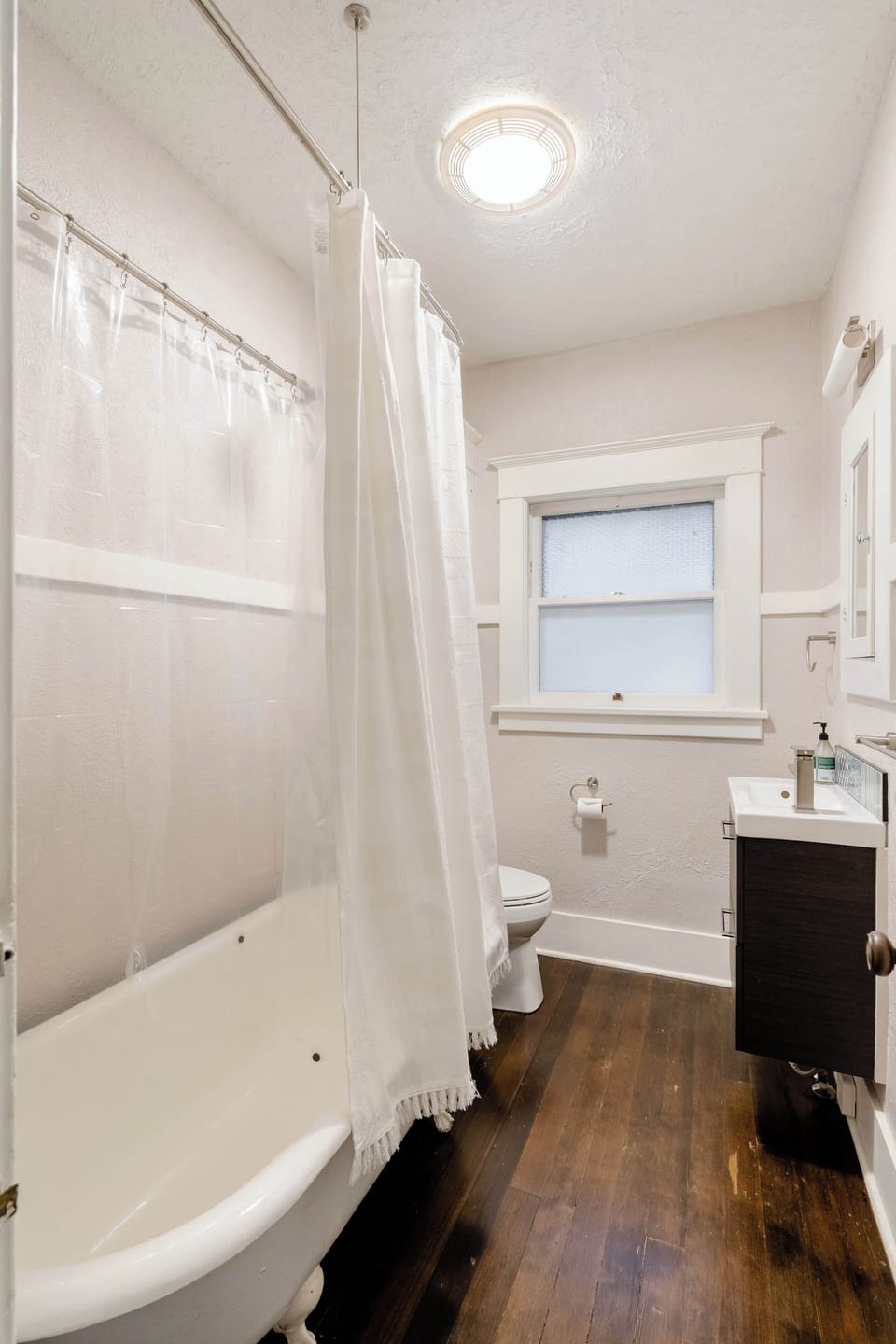 Bathroom with a bathtub, shower curtain and toilet.