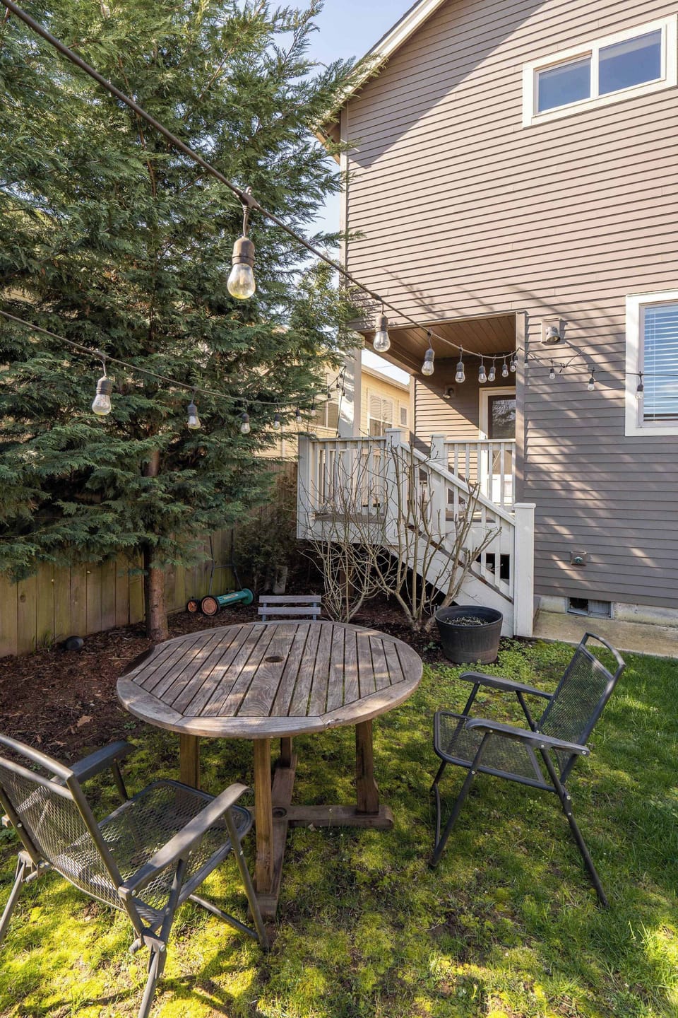 Outdoor table and chairs beside a fence and deck stairs.