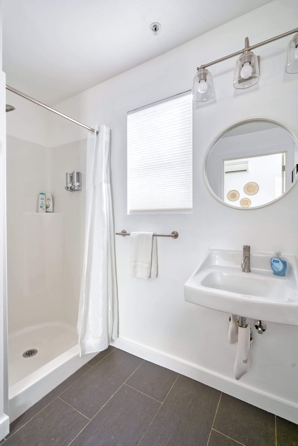 Bathroom with shower enclosure, wall-mounted sink and mirror.