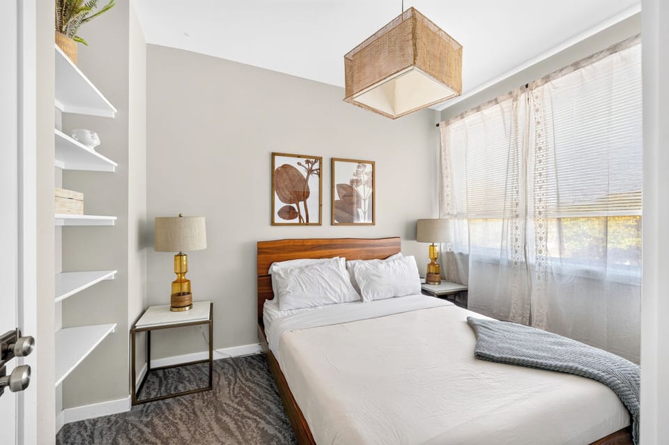 Bedroom with wood bed frame, bedside tables, and open shelving.
