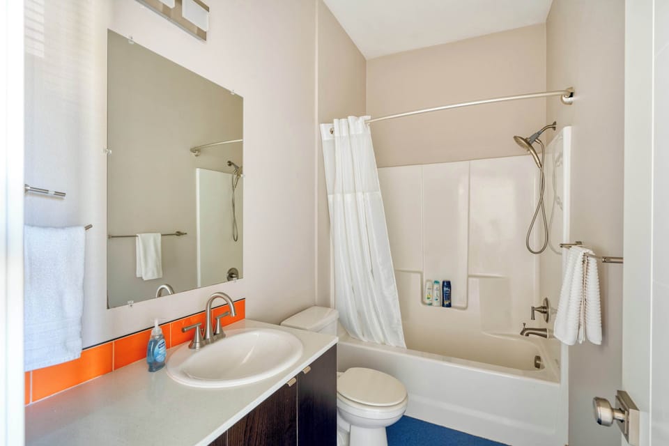 Bathroom with a bathtub, shower fixture, vanity, and toilet.
