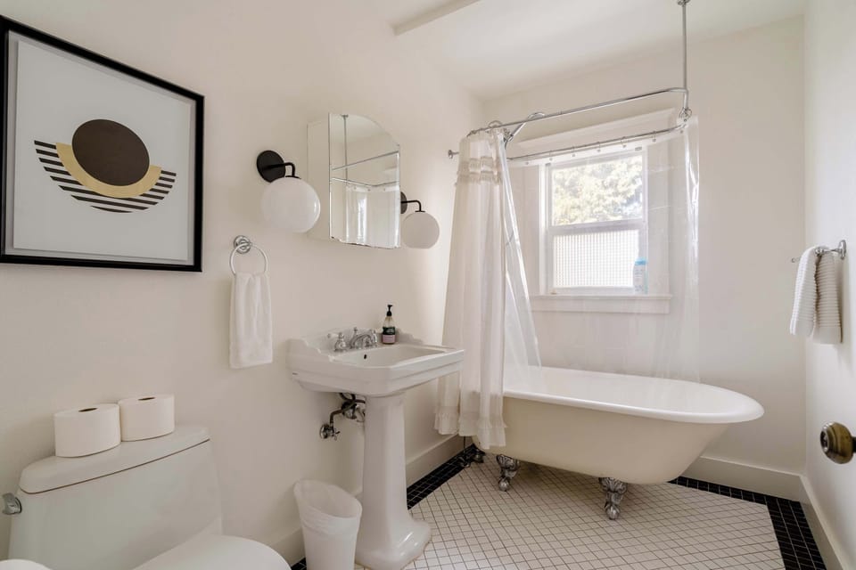 Bathroom with a clawfoot bathtub and shower, pedestal sink, and toilet.