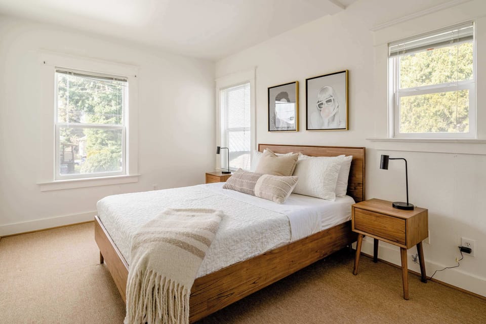 Bedroom with a wooden bed frame and windows.