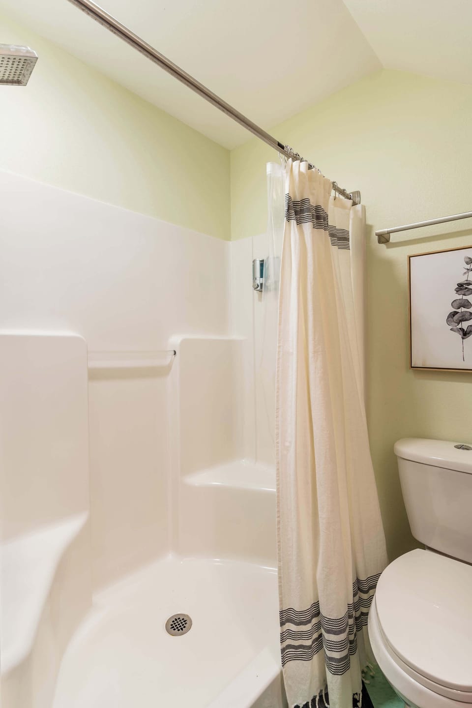 Bathroom with shower tray, curtain, and toilet.