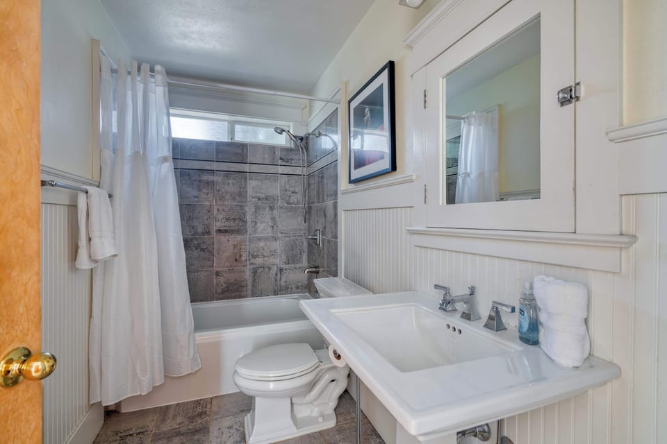 Bathroom with a bathtub and shower beside a pedestal sink.