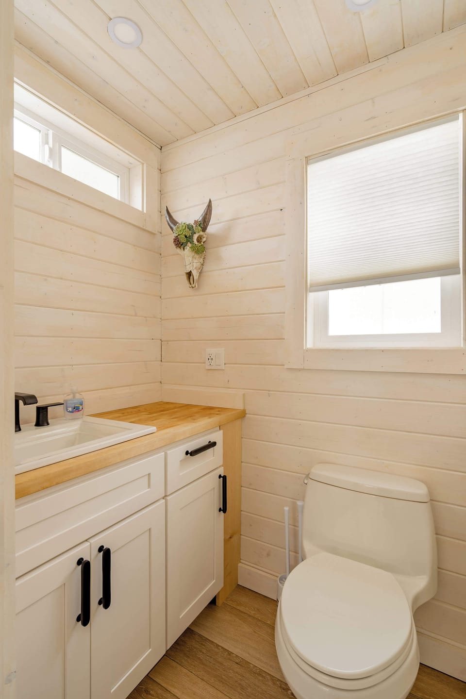 Bathroom with vanity, toilet, and window.