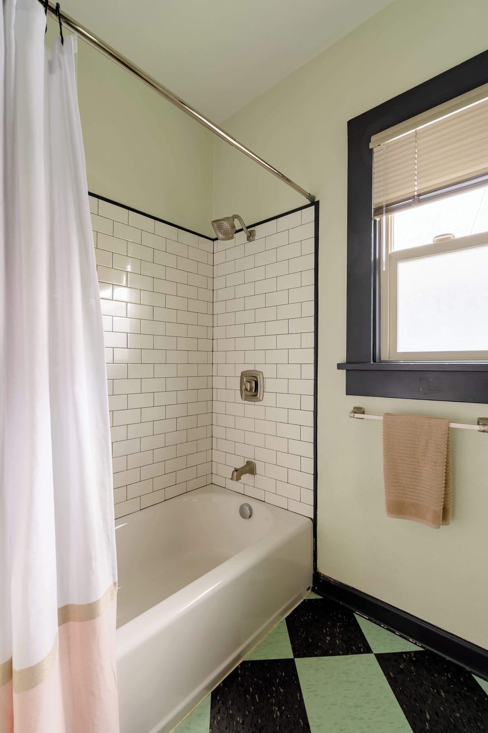 Tiled bathtub and shower beside a window.