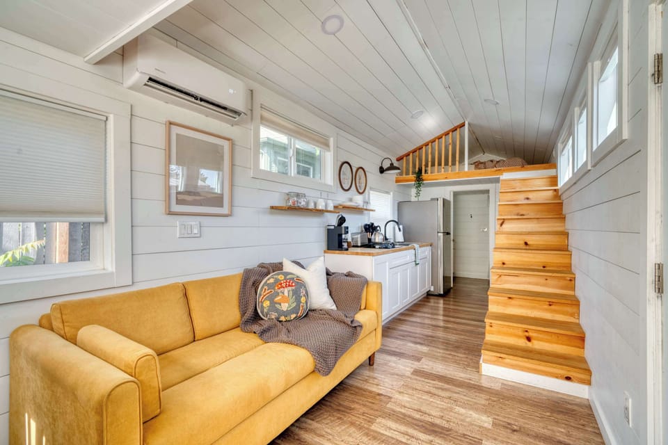 Living room with yellow sofa and loft stairs.